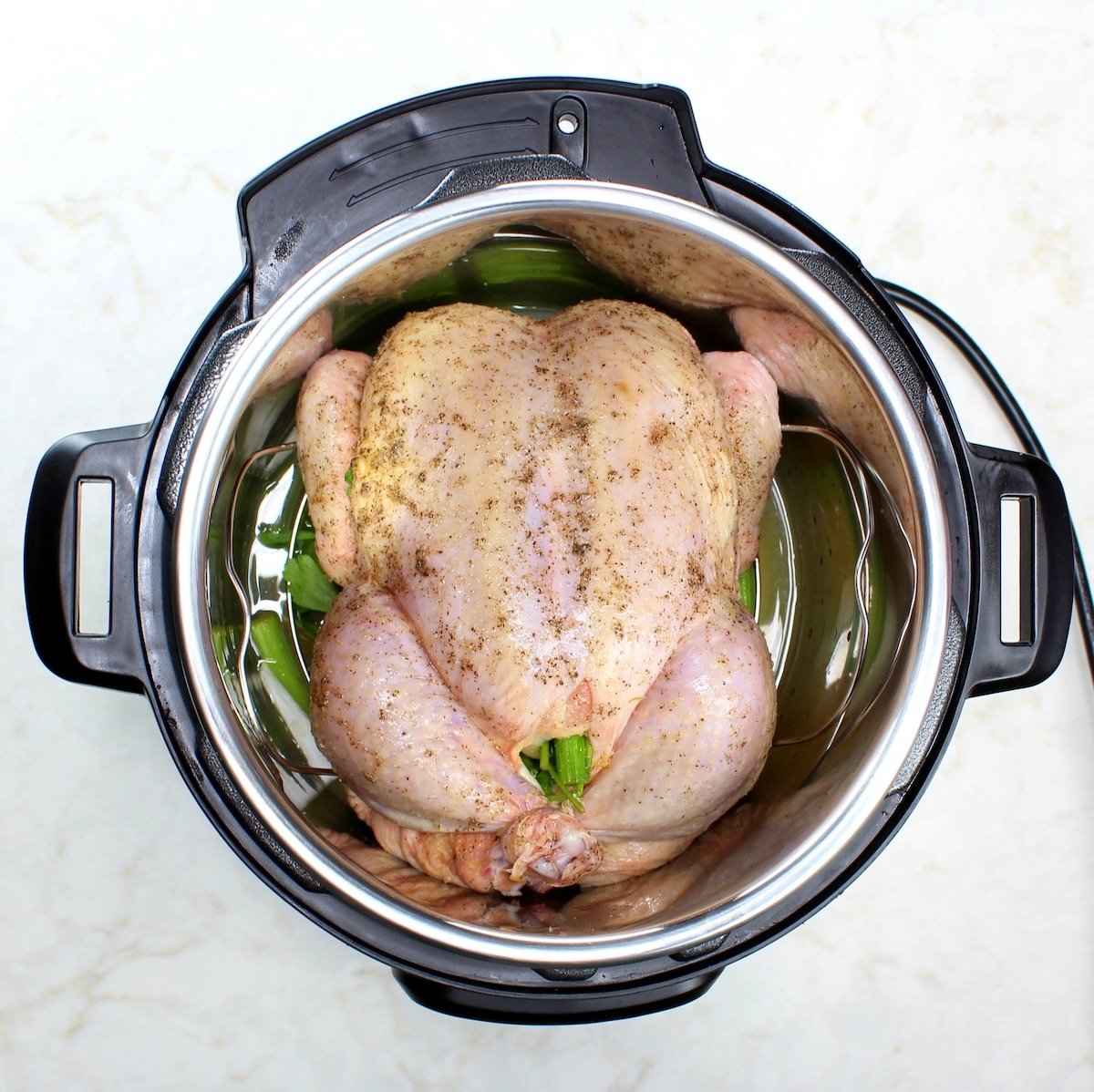 Whole chicken recipe - a raw chicken stuffed with herbs and veggies in the Instant Pot.