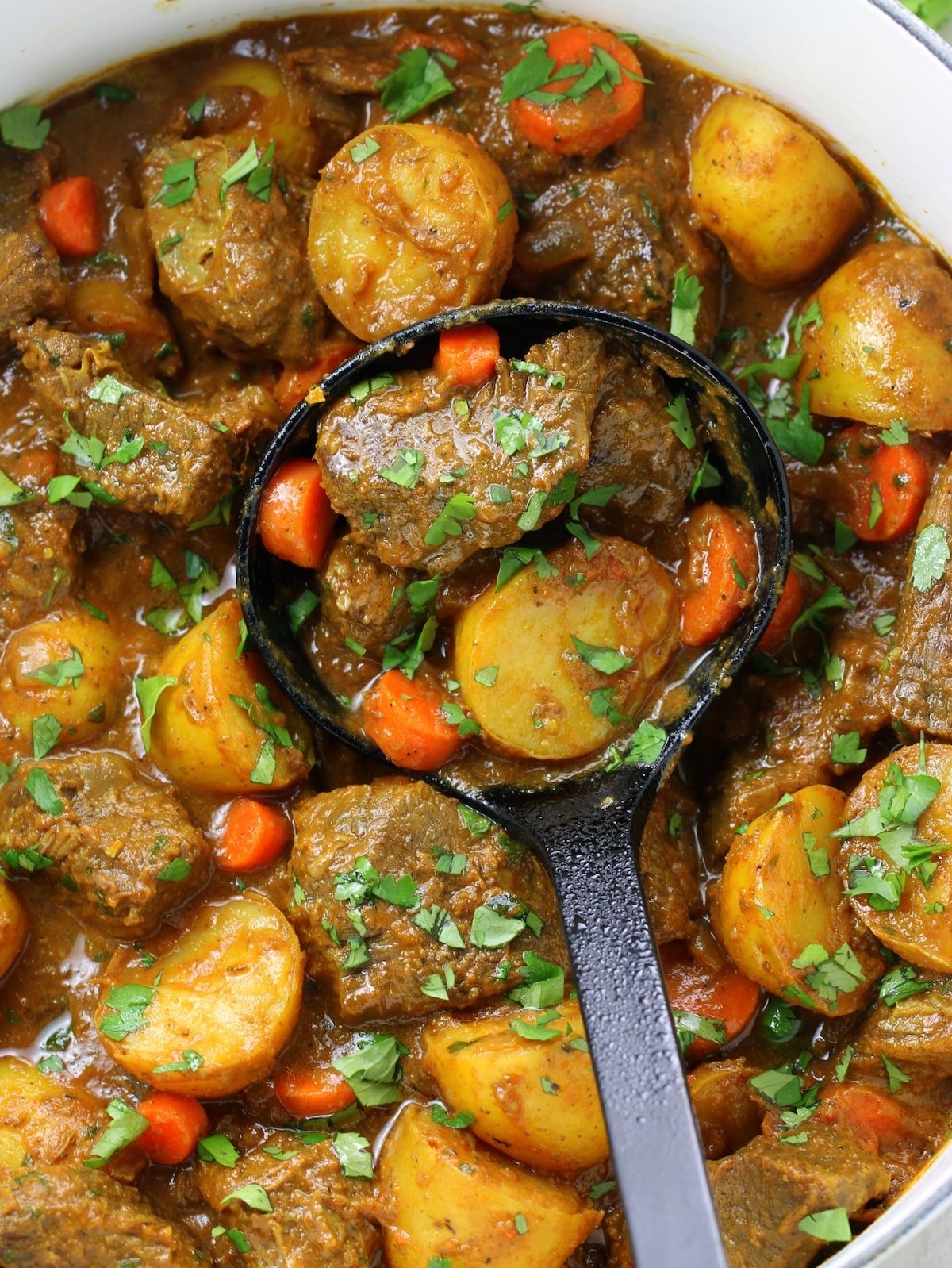 A close-up photo of a pot with cooked chuck roast, potatoes, beef stock and spices.