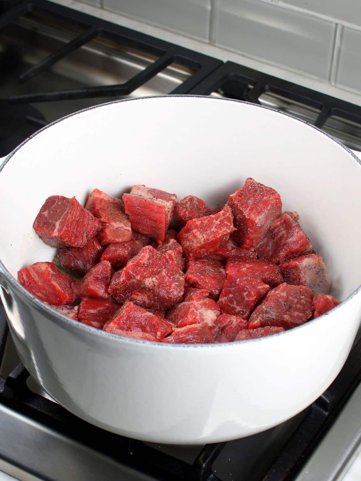 Searing cubes of chuck roast in a large pot on the stove.