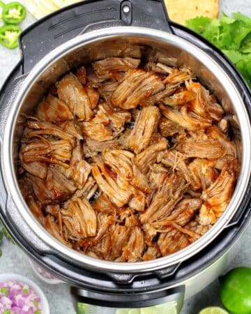 A 1200x1200 photo of an Instant pot full of pork carnitas meat.