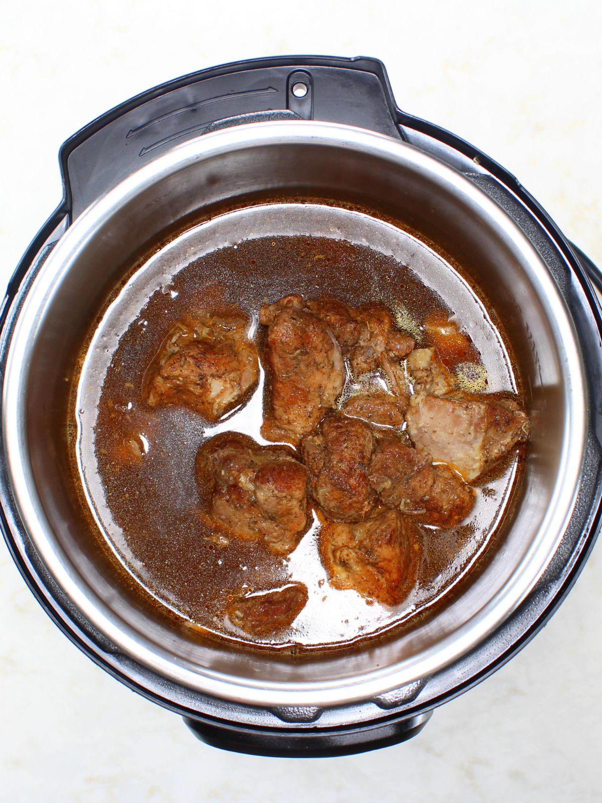 The onions, seared meat and chicken broth in the Instant Pot ready to cook.