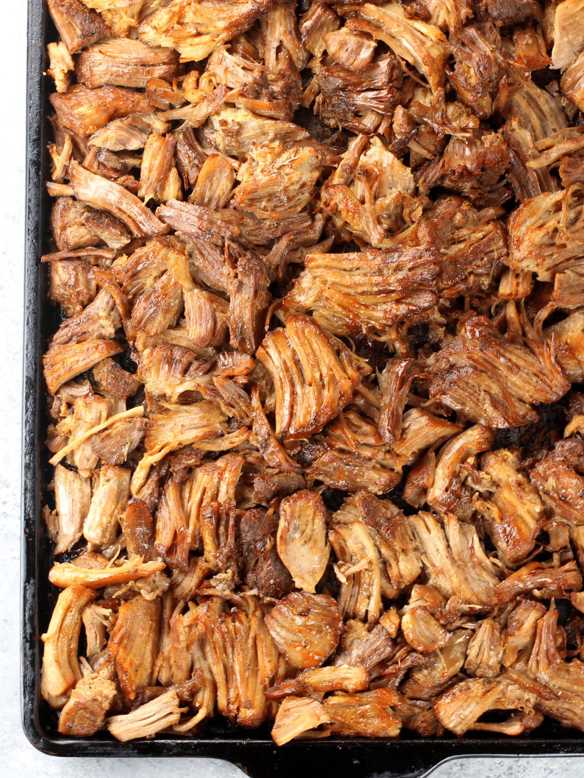 A baking sheet full of the pulled meat broiled until crispy.