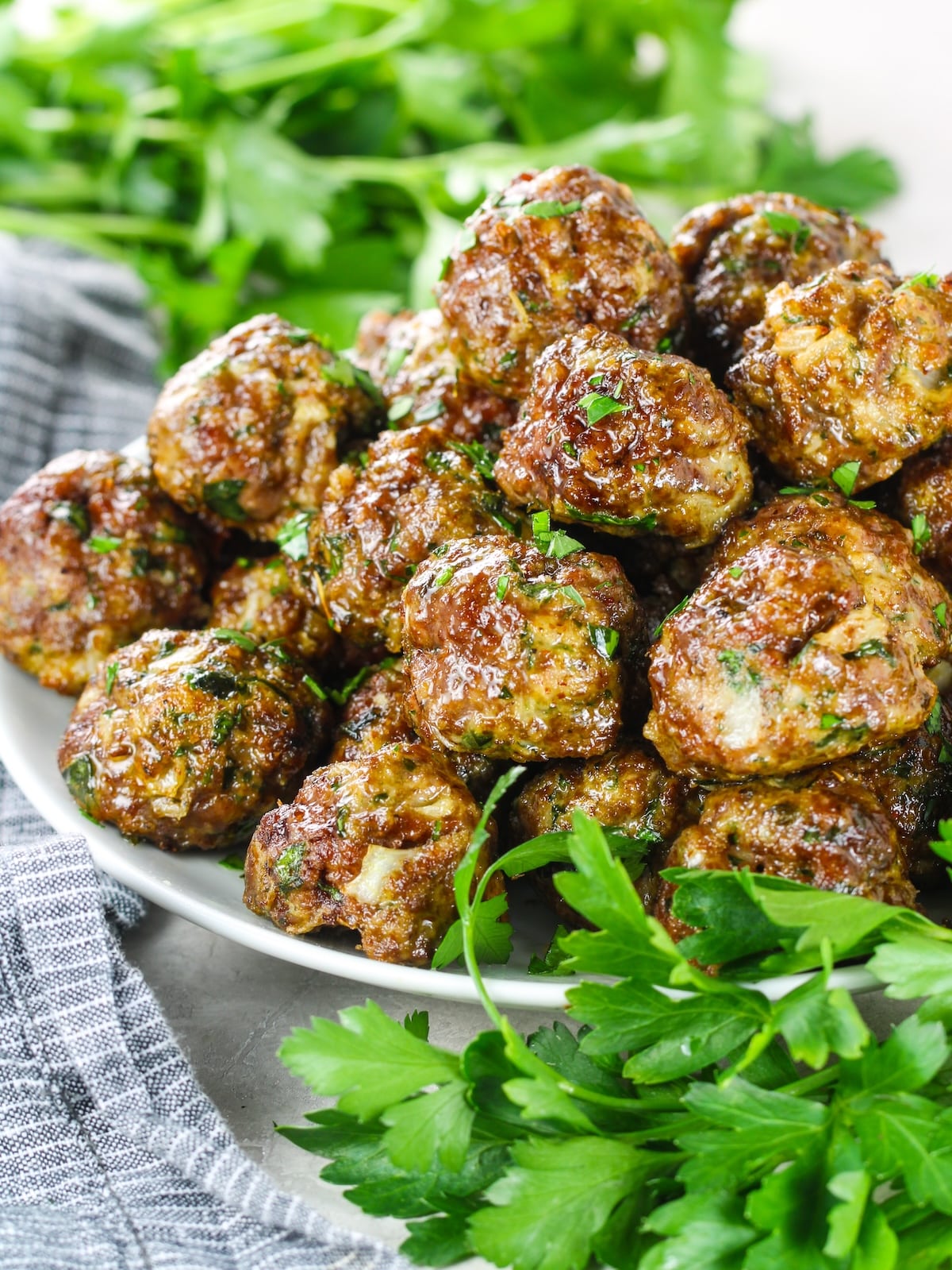 A close-up photo of a platter of Italian meatballs with parsley as a garnish.