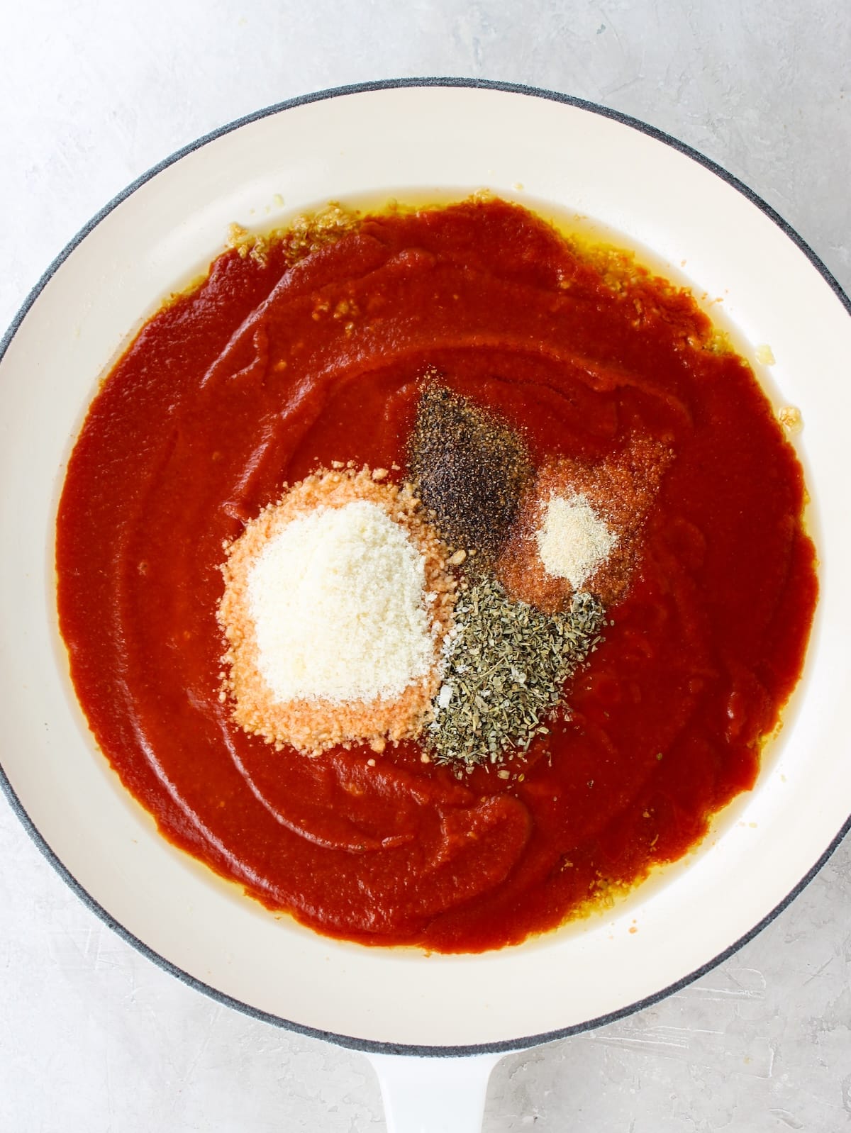 How to make tomato sauce - tomato sauce, parmesan cheese, pepper, Italian seasoning and onion powder cooking in a pan.