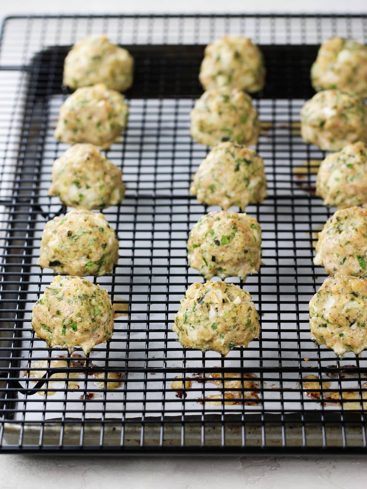 Baked meatballs on a wire rack.