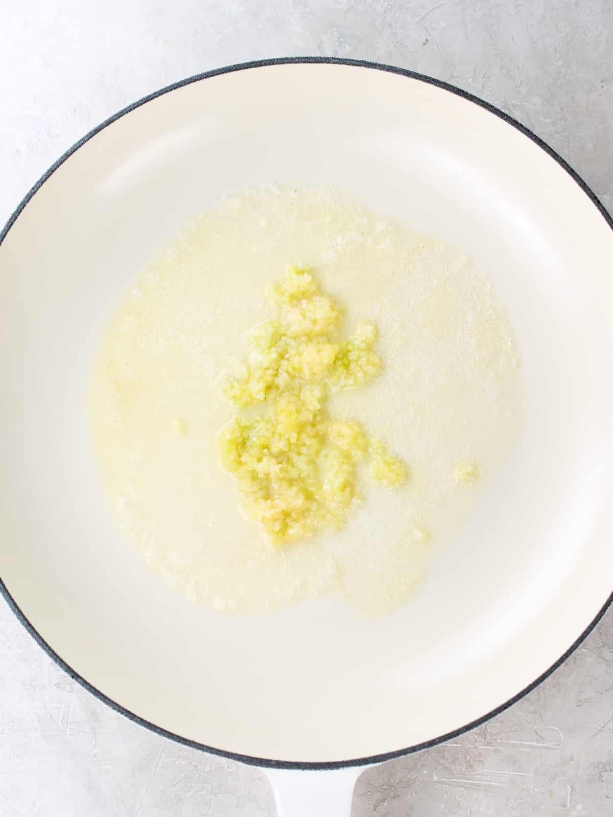 Sautéing garlic in melted butter in a pan.