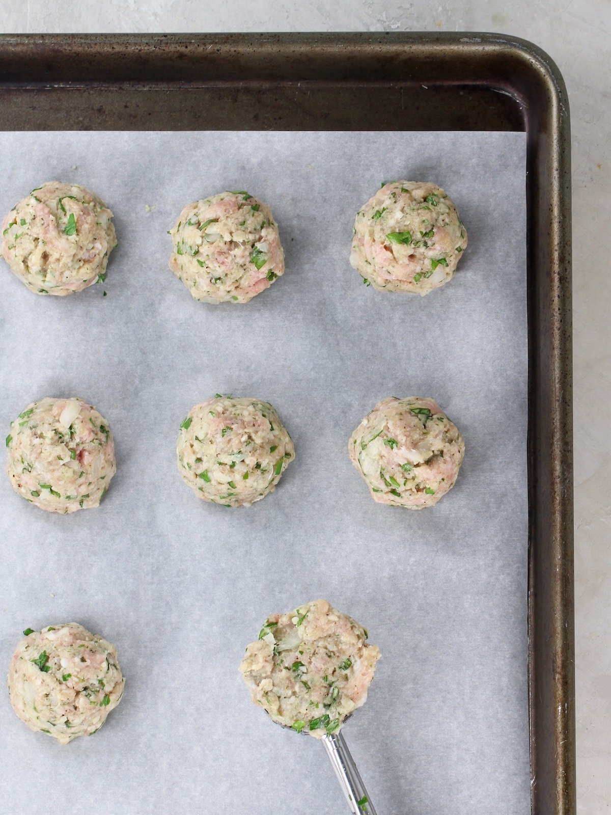 An Italian meatball recipe  - scooped out on a baking sheet.