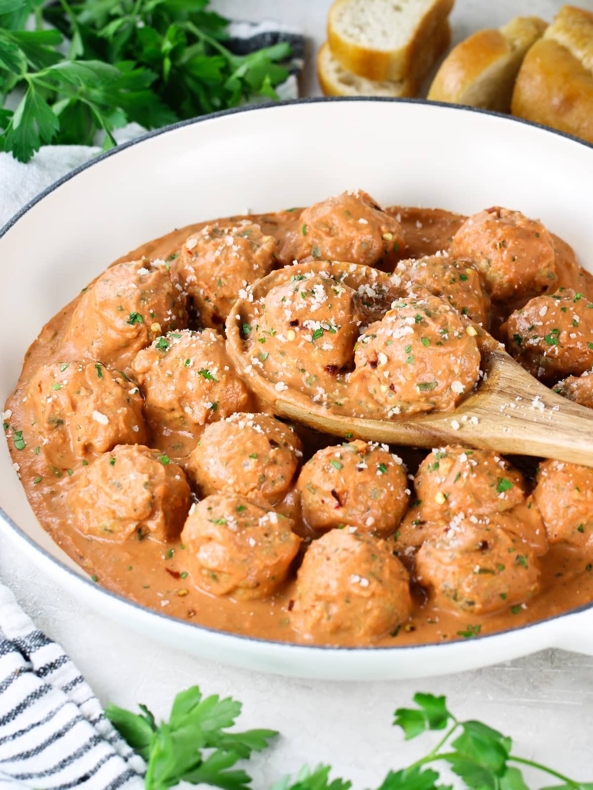 A close up photo of baked meatballs in a pan with sauce.