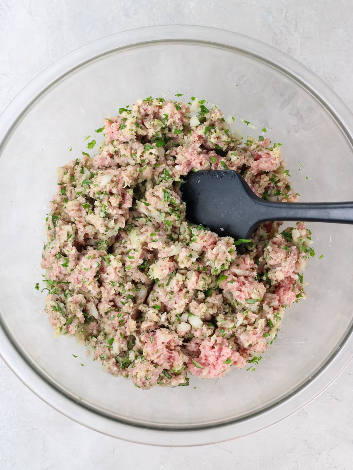 Italian meatball recipe ingredients mixed together in a large bowl.