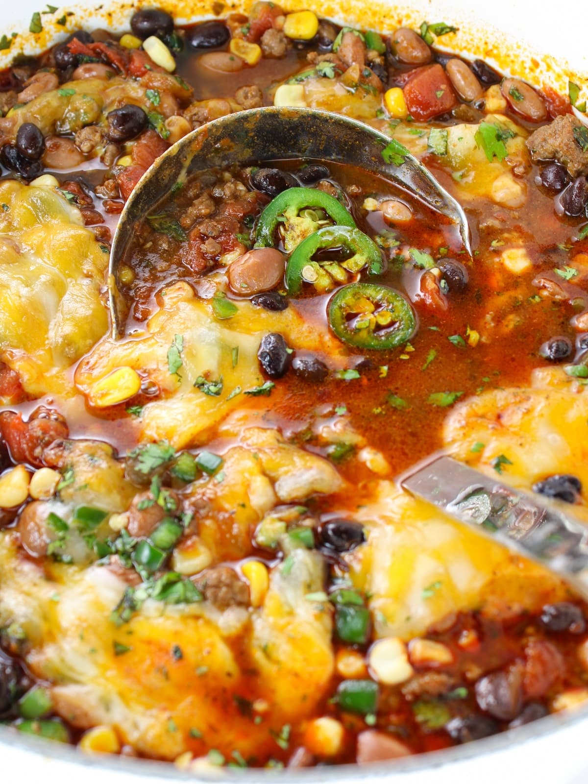 A close-up photo of taco soup with toppings in a large pot.