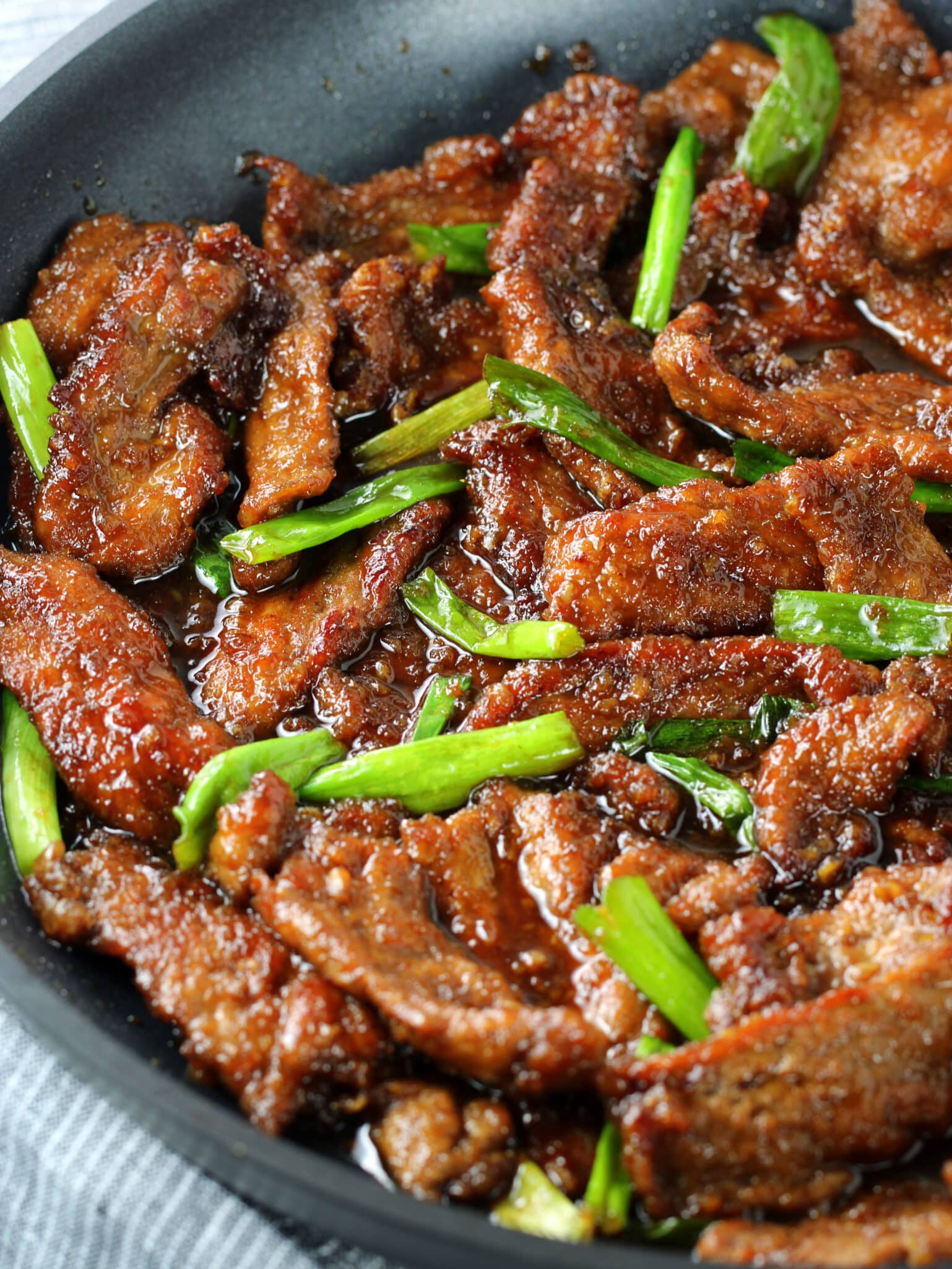 A close up pan of beef, sauce and onions cooked.