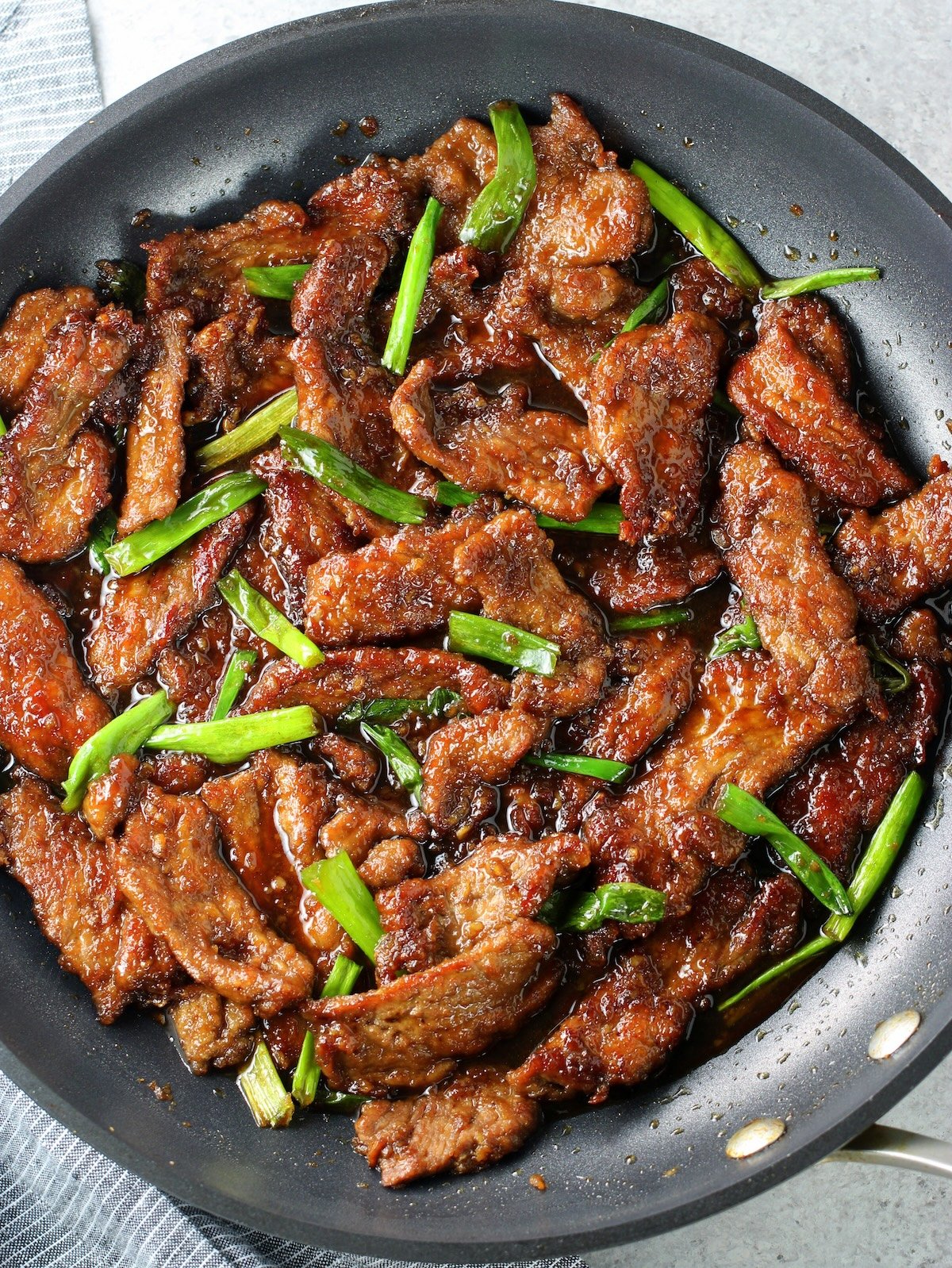 How to Cook 30-Minute Mongolian Beef - Recipe and Image A pan of cooked thinly sliced steak tossed in Mongolian beef sauce with green onions.