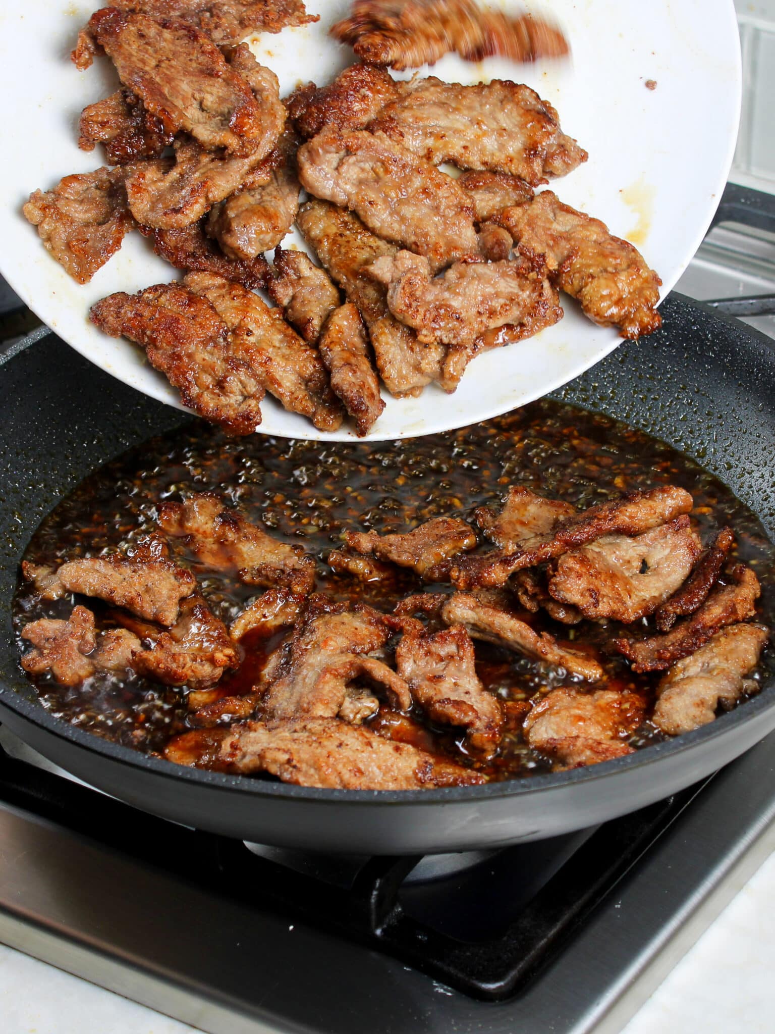 Adding pan fried slice beef into the mongolian sauce.