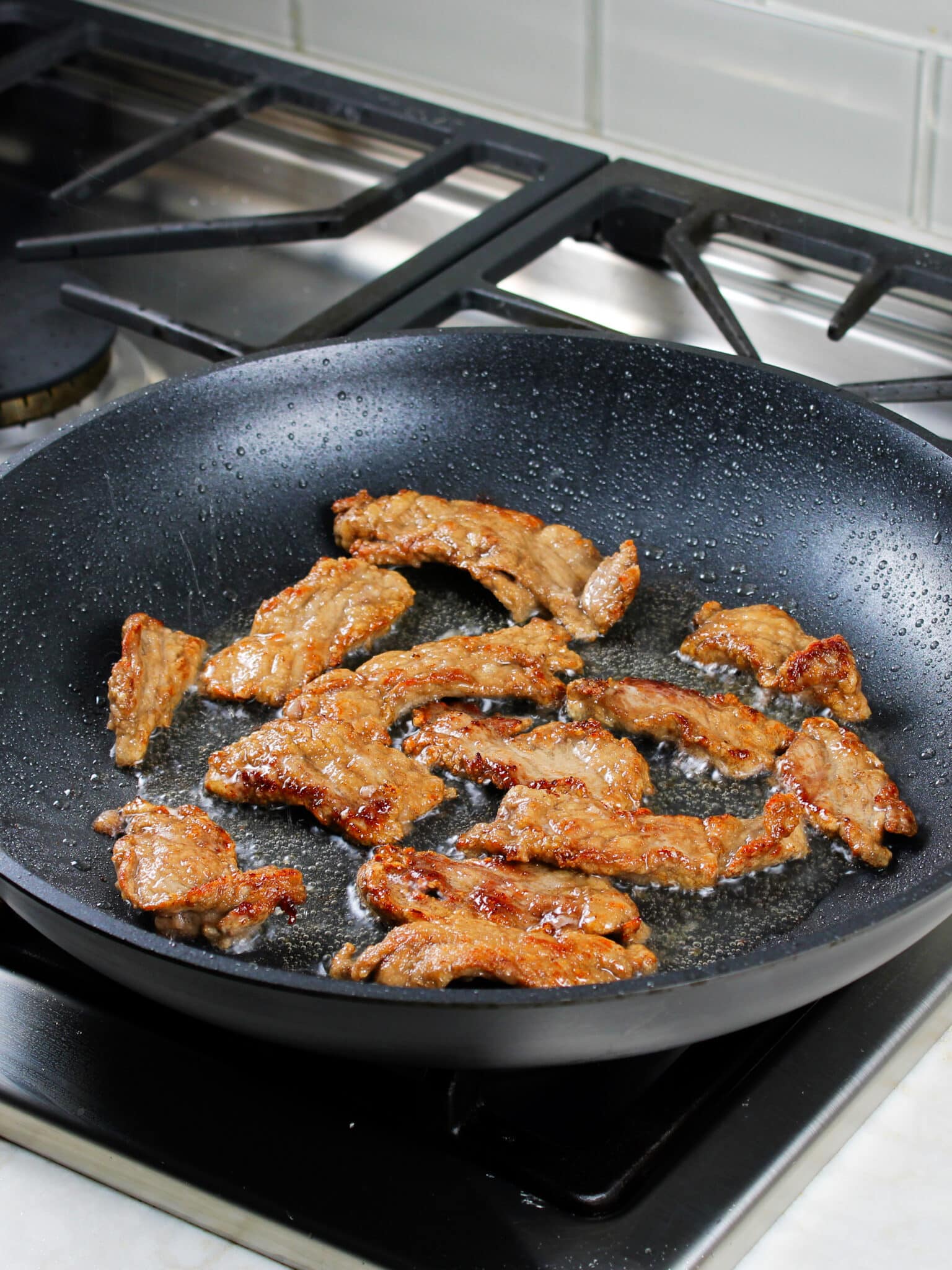 Thinly sliced beef being pan fried.