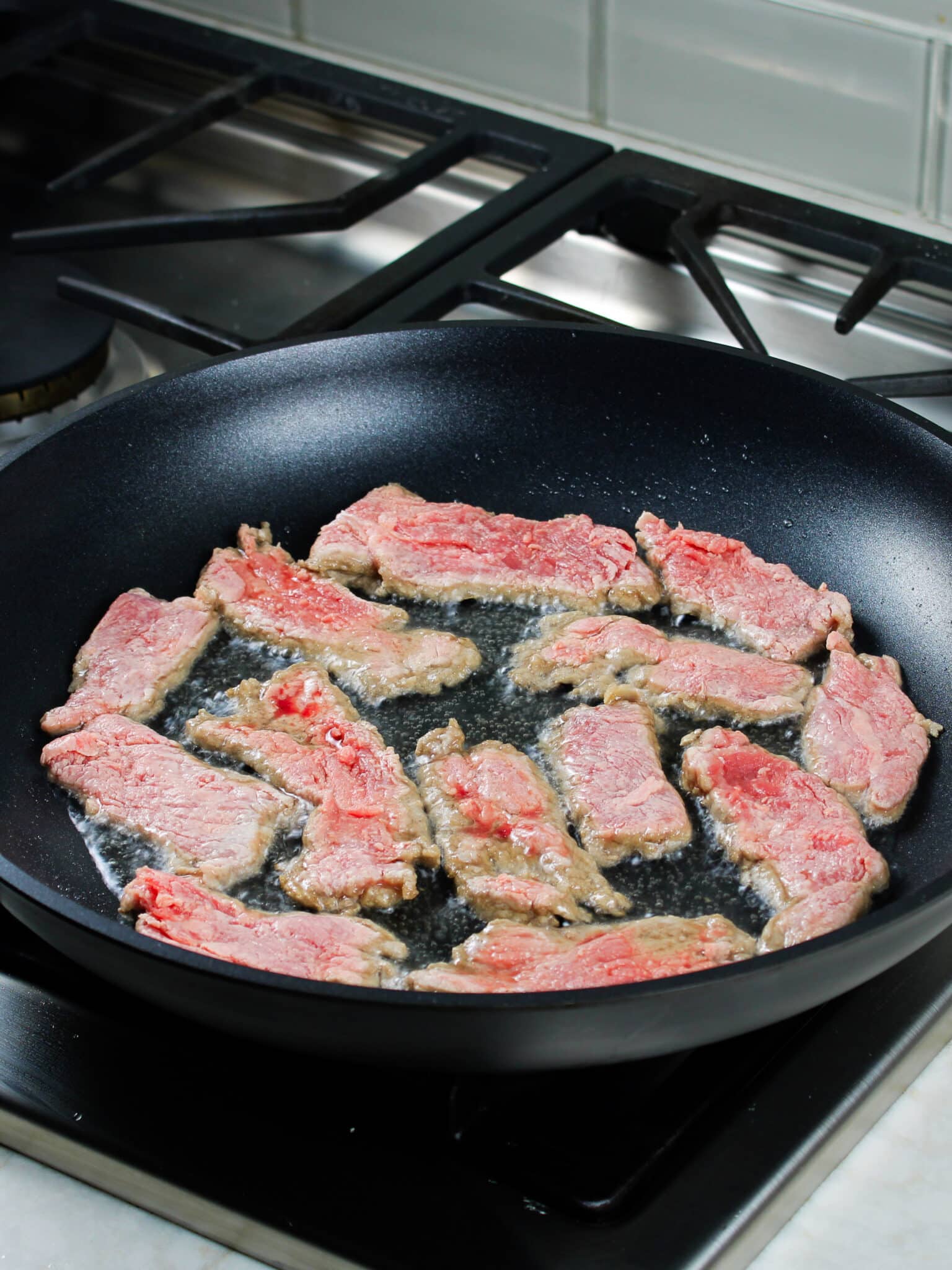 Thinly sliced beef being pan fried.