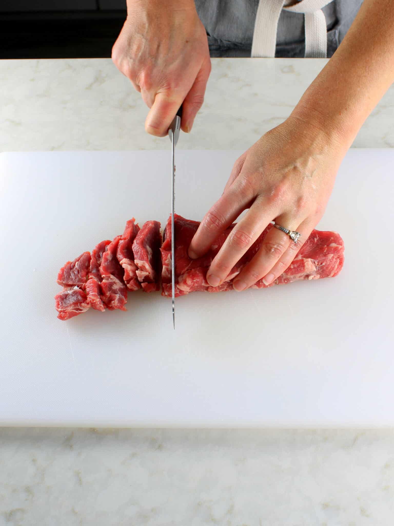 Cutting the steak into thinly slices.