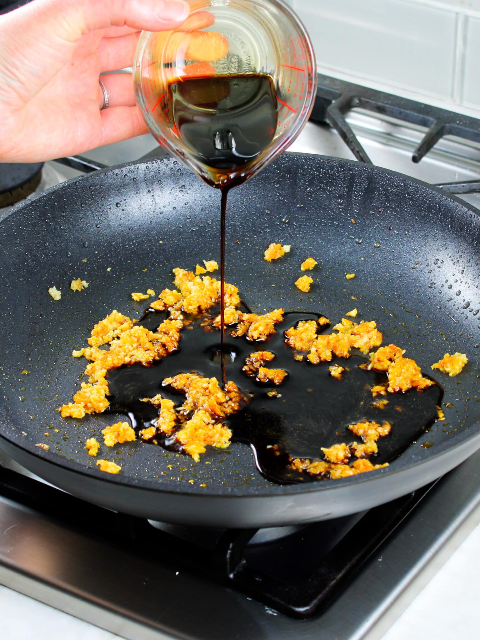 Pouring Tamari (gluten-free soy sauce) into the sauteeing garlic and ginger.