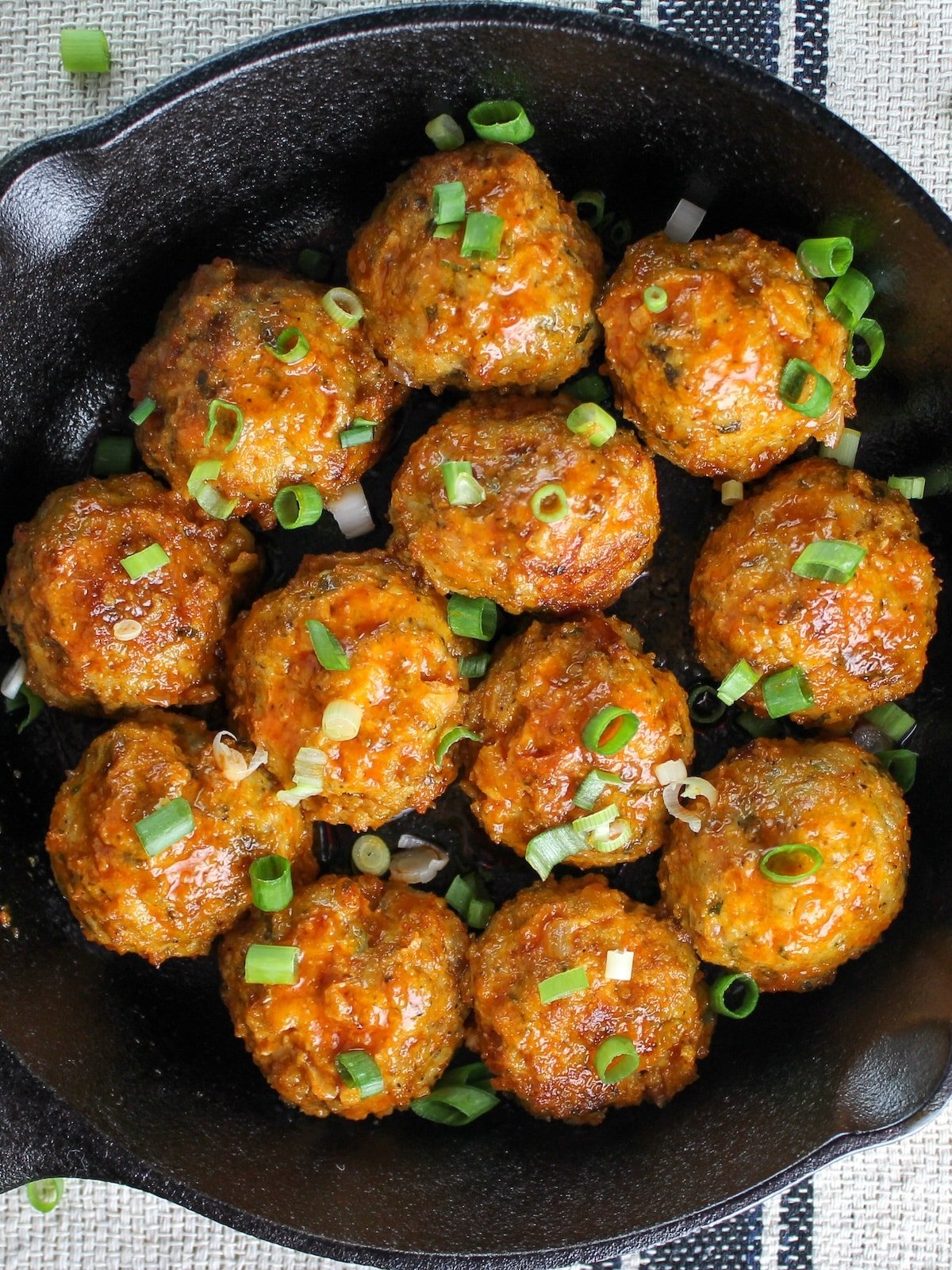 Meatballs in a pan tossed with buffalo sauce.