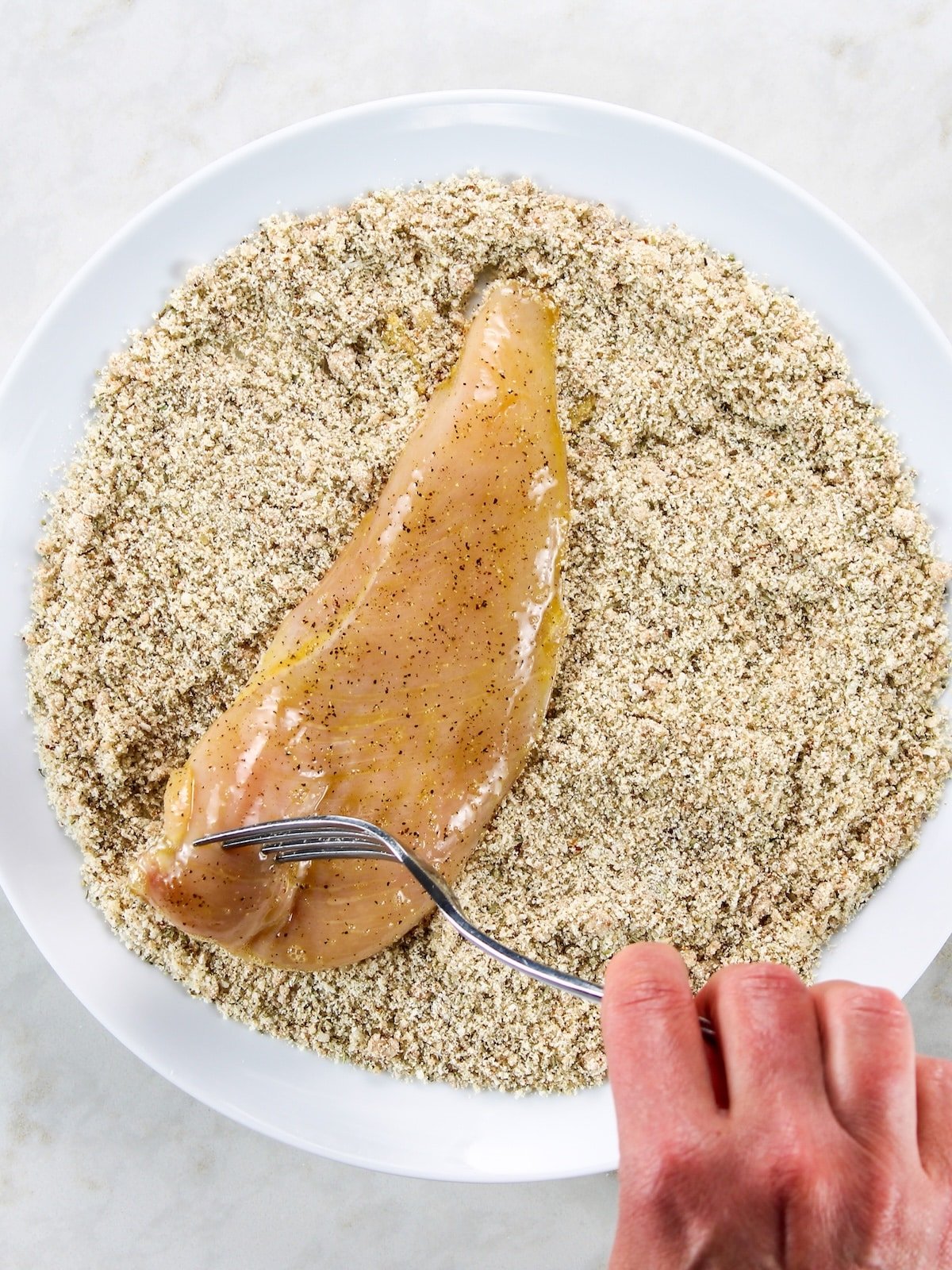 Dipping egg-washed chicken breast in a plate of almond meal & parmesan cheese Gluten-Free Chicken Parmesan - chicken cutlets dipped in an egg mixture and coated with almond meal bread crumbs mixture.