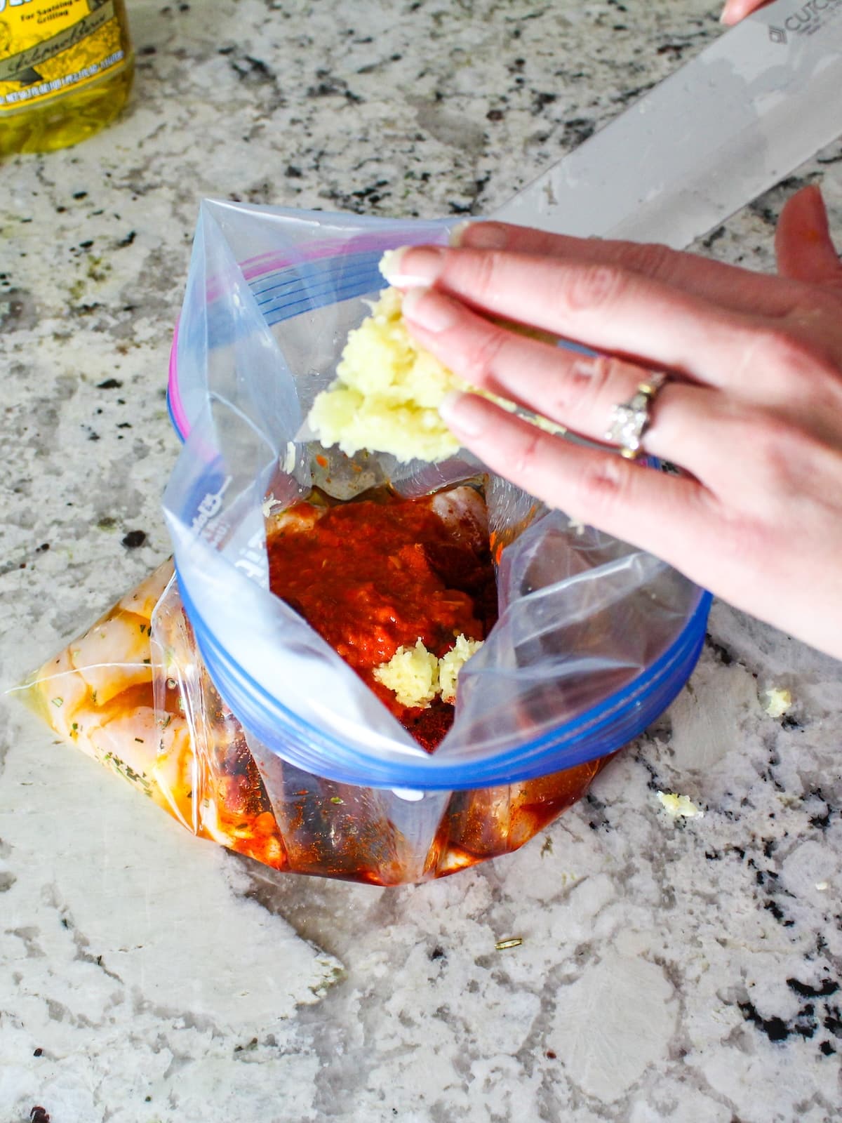 Adding minced garlic to the marinade for the chicken.