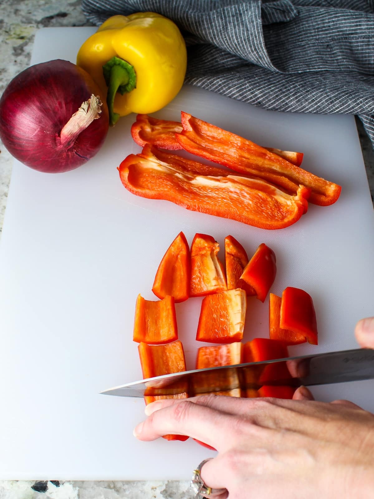 Chopping up red and yellow peppers on a cutting board.