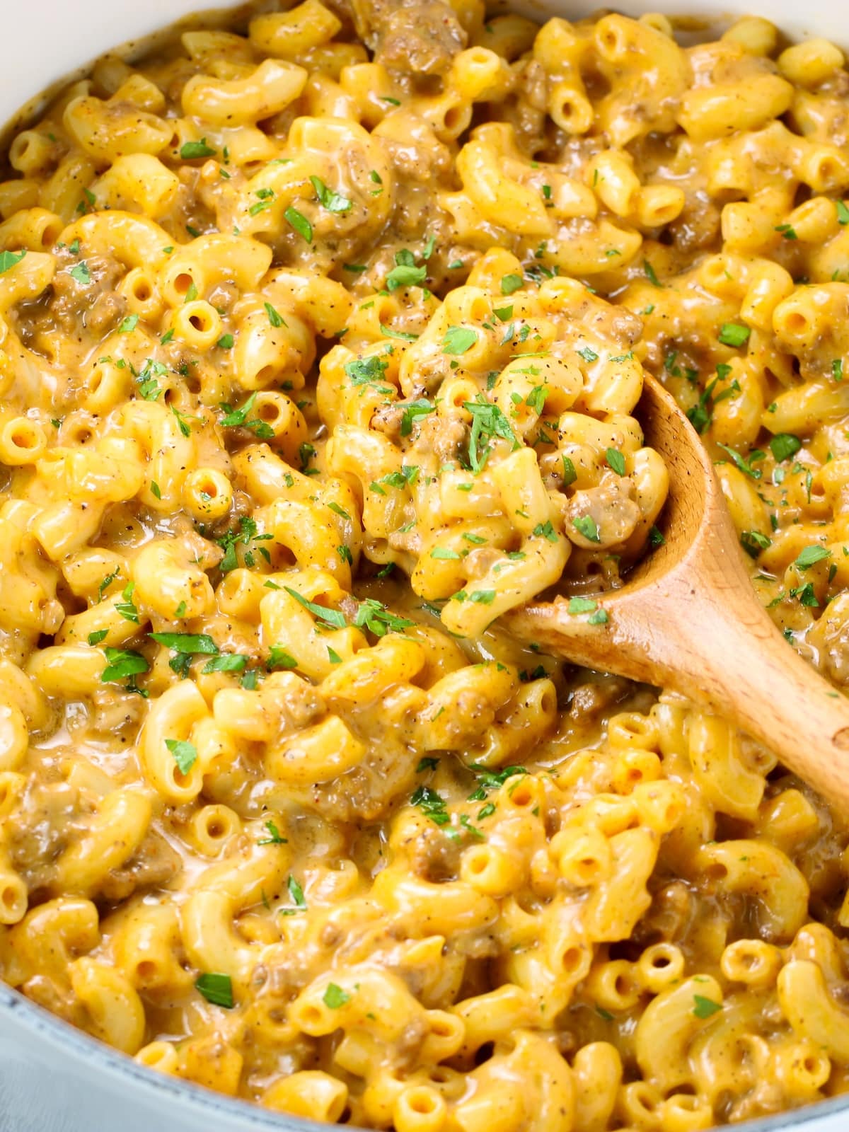 A Dutch oven with delicious cheeseburger mac sprinkled with chopped parsley.