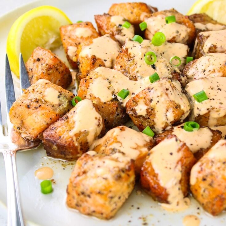 A close up photo of air fried salmon bites on a plate with bang Bang Sauce.