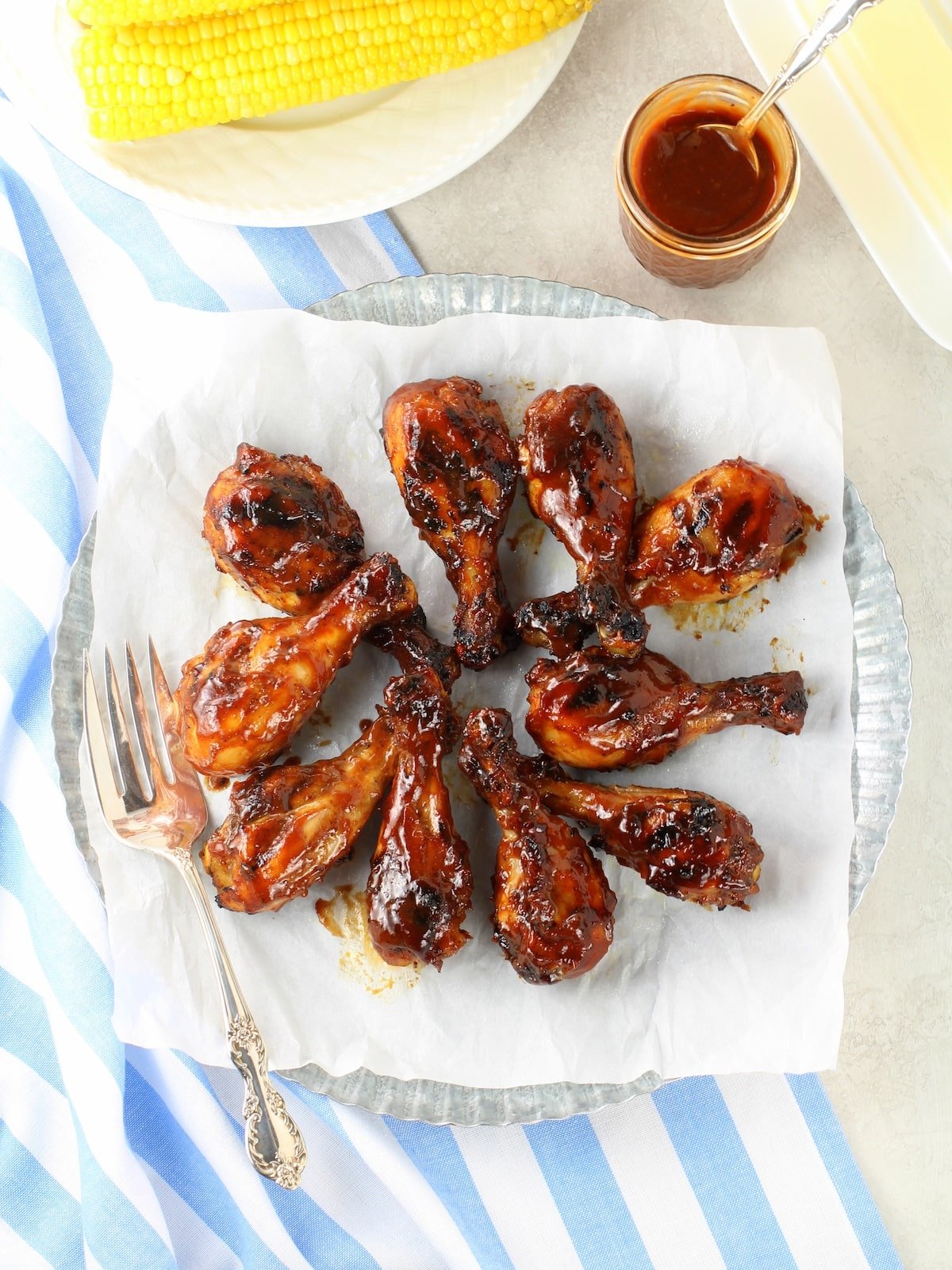 Grilled BBQ Chicken Drumsticks Recipe Chicken legs with extra BBQ sauce and corn on the cobb.