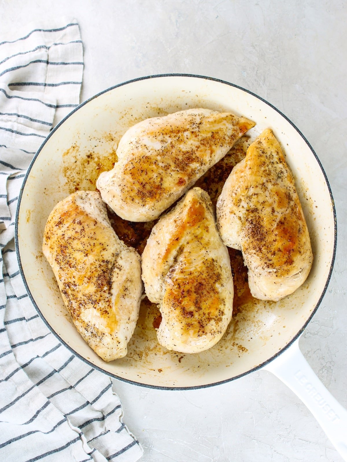 Bonelss skinless chicken breasts that have been seared in a skillet.