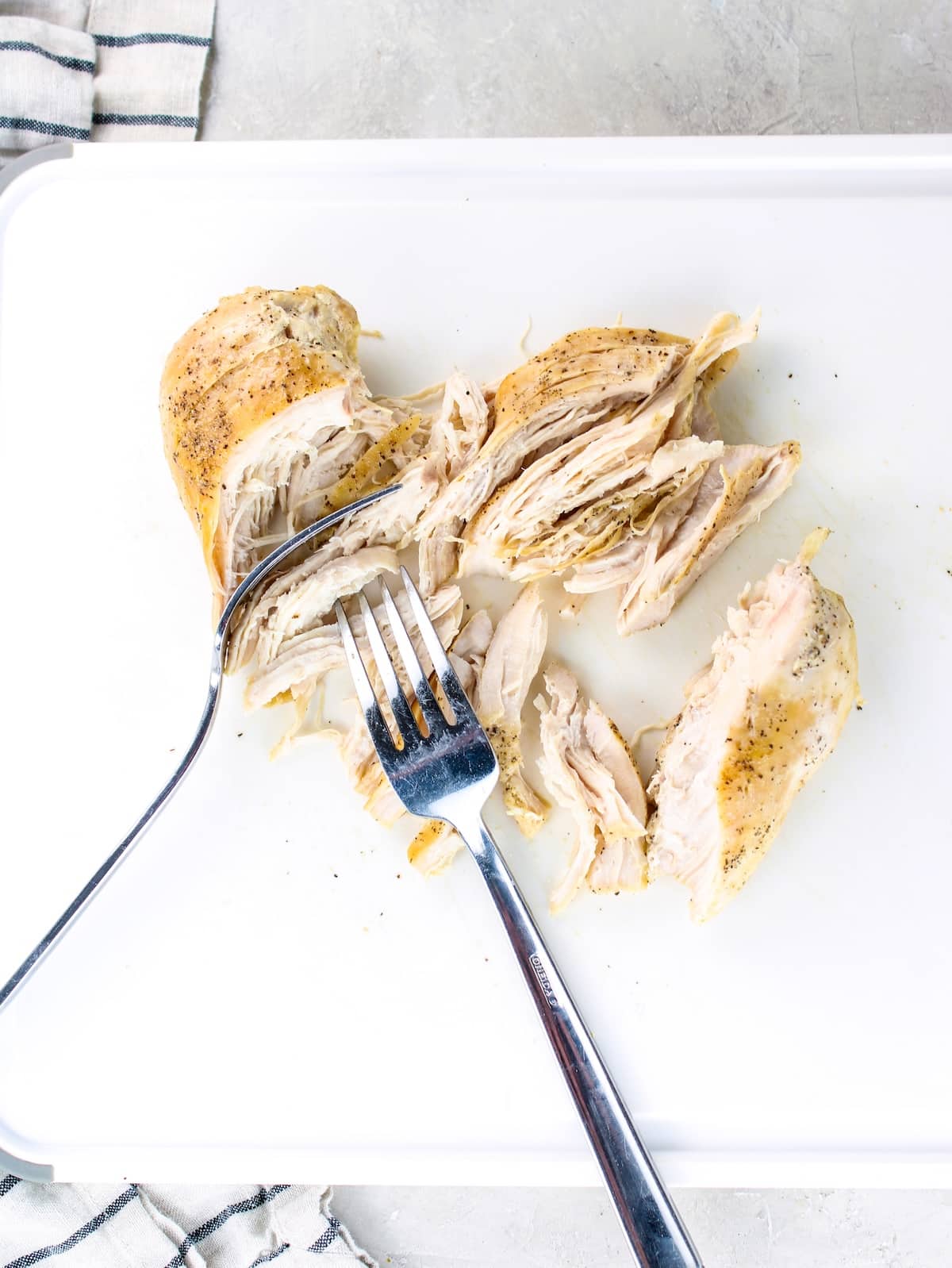 Easy Shredded Chicken Recipe - chicken breasts being pulled with two forks.