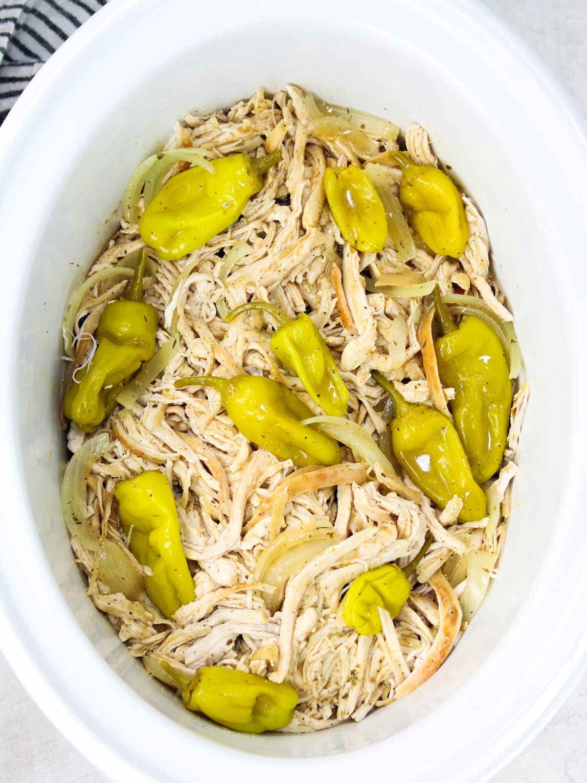 Mississippi Chicken with pepperoncini peppers and onions cooked on low in the crockpot.