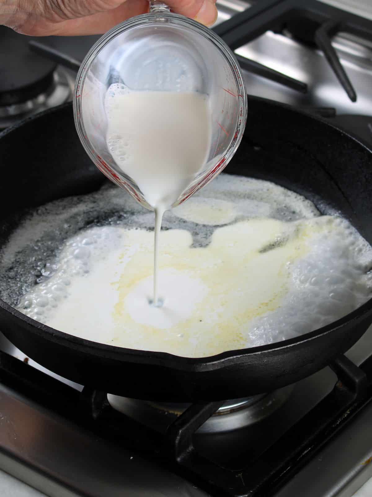 Adding milk to melted butter in a skillet.