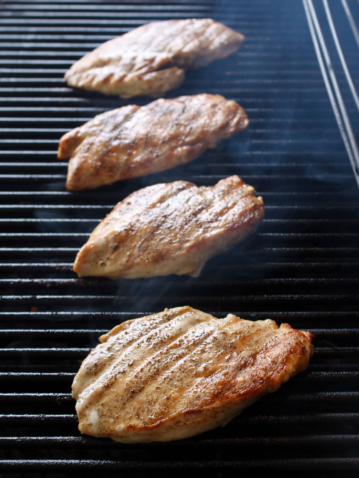 Chicken breasts grilling on grill.
