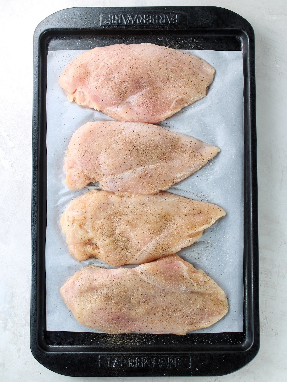 Chicken breasts on baking sheet before cooking.