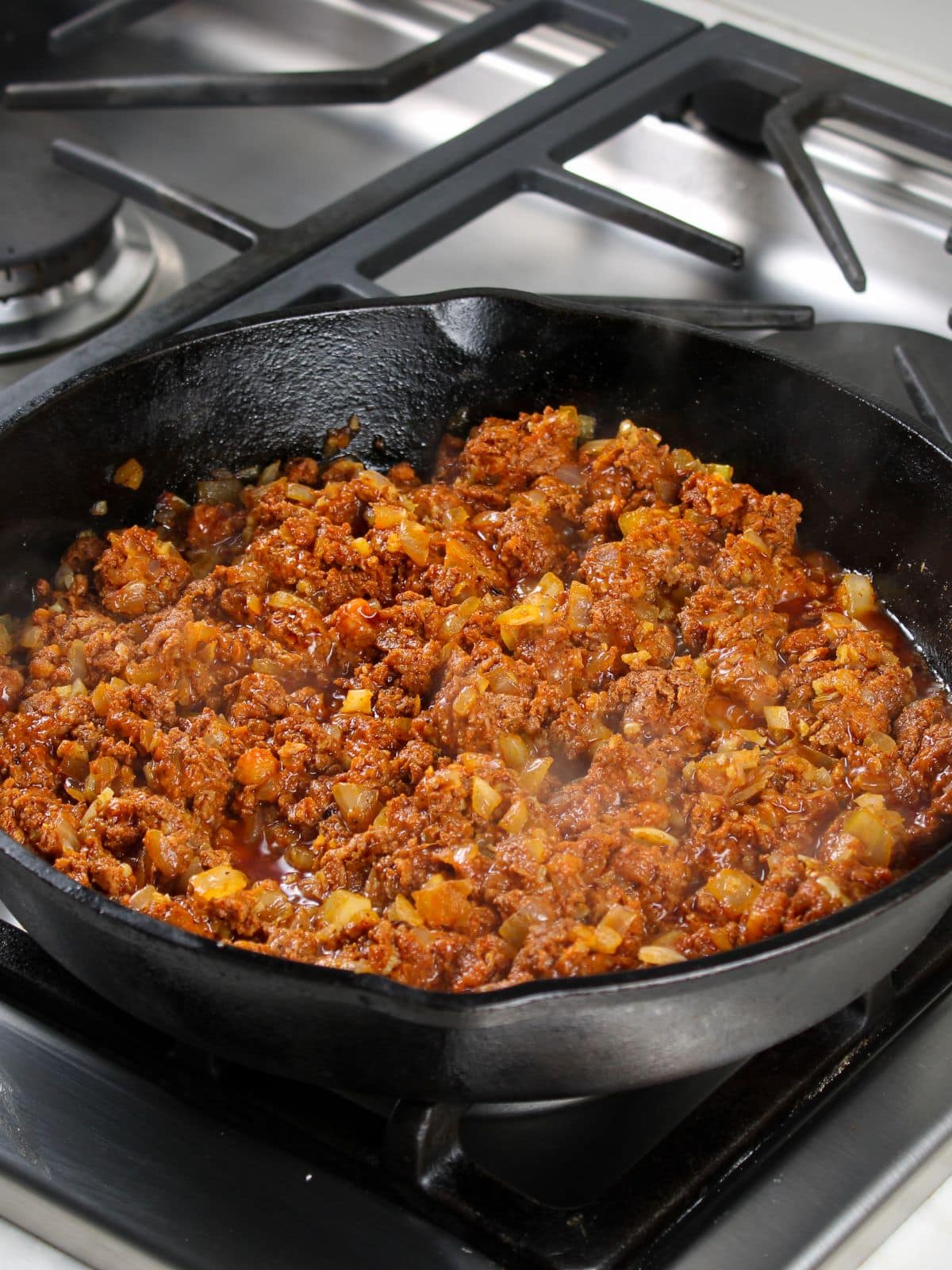 Chorizo cooking in cast iron skillet on the stovetop for chori pollo.
