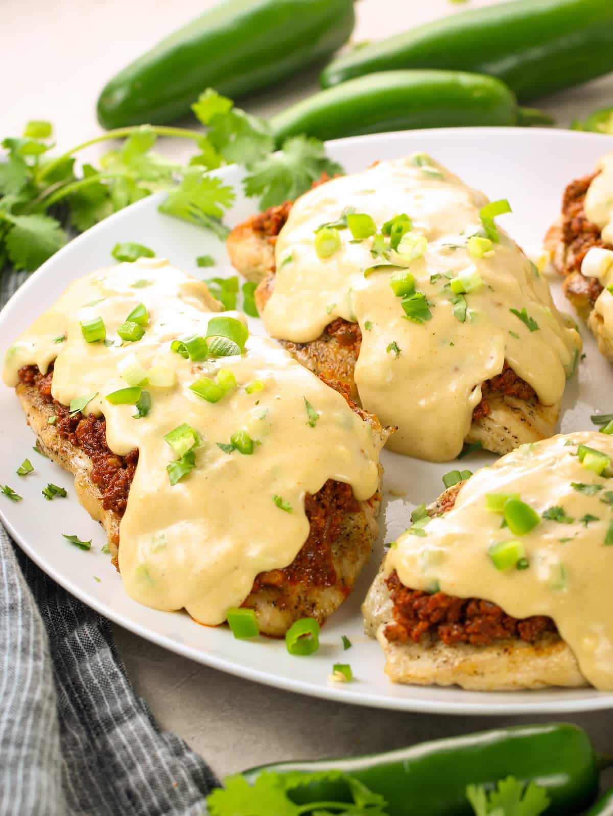 A plate with grilled chicken, sautéed chorizo, and a cheesy topping.
