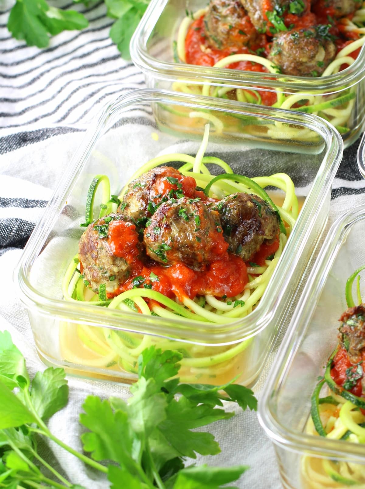A glass meal prep containers with zucchini noodles, marinara sauce and easy baked turkey meatballs.