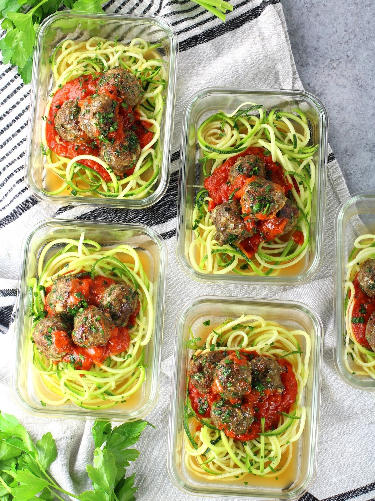 Glass meal prep containers with zucchini noodles, marinara sauce and healthy baked turkey meatballs.
