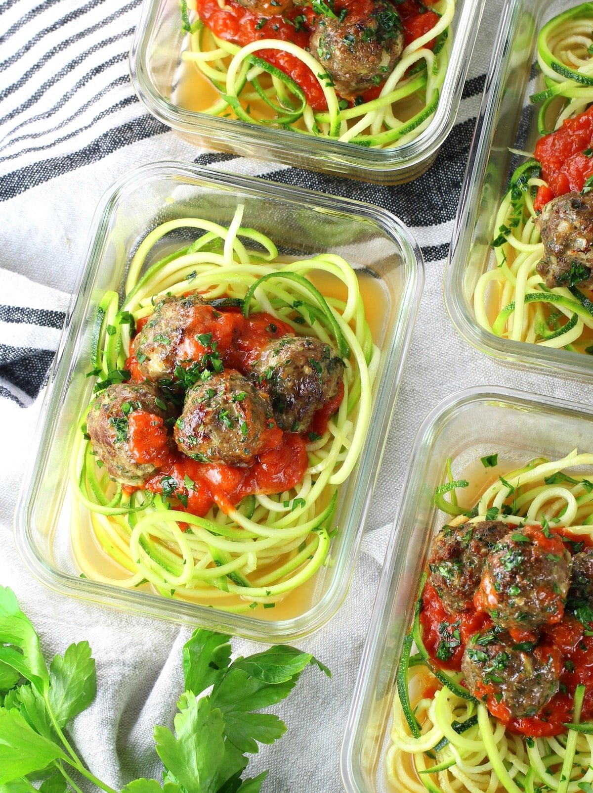 Glass meal prep containers with zoodles, marinara sauce and healthy turkey meatballs.