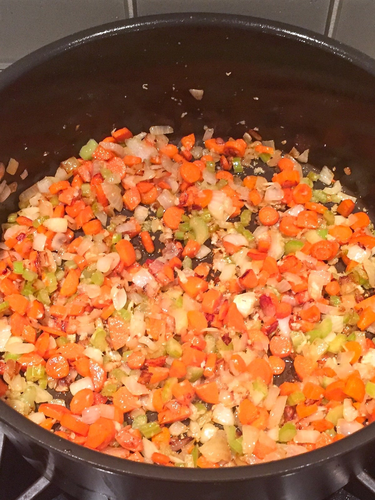 Chopped carrots, onions, and celery cooked in a large pot.