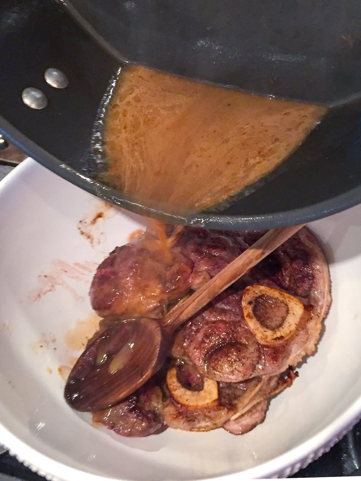 Deglazing juices being poured over the seared veal.