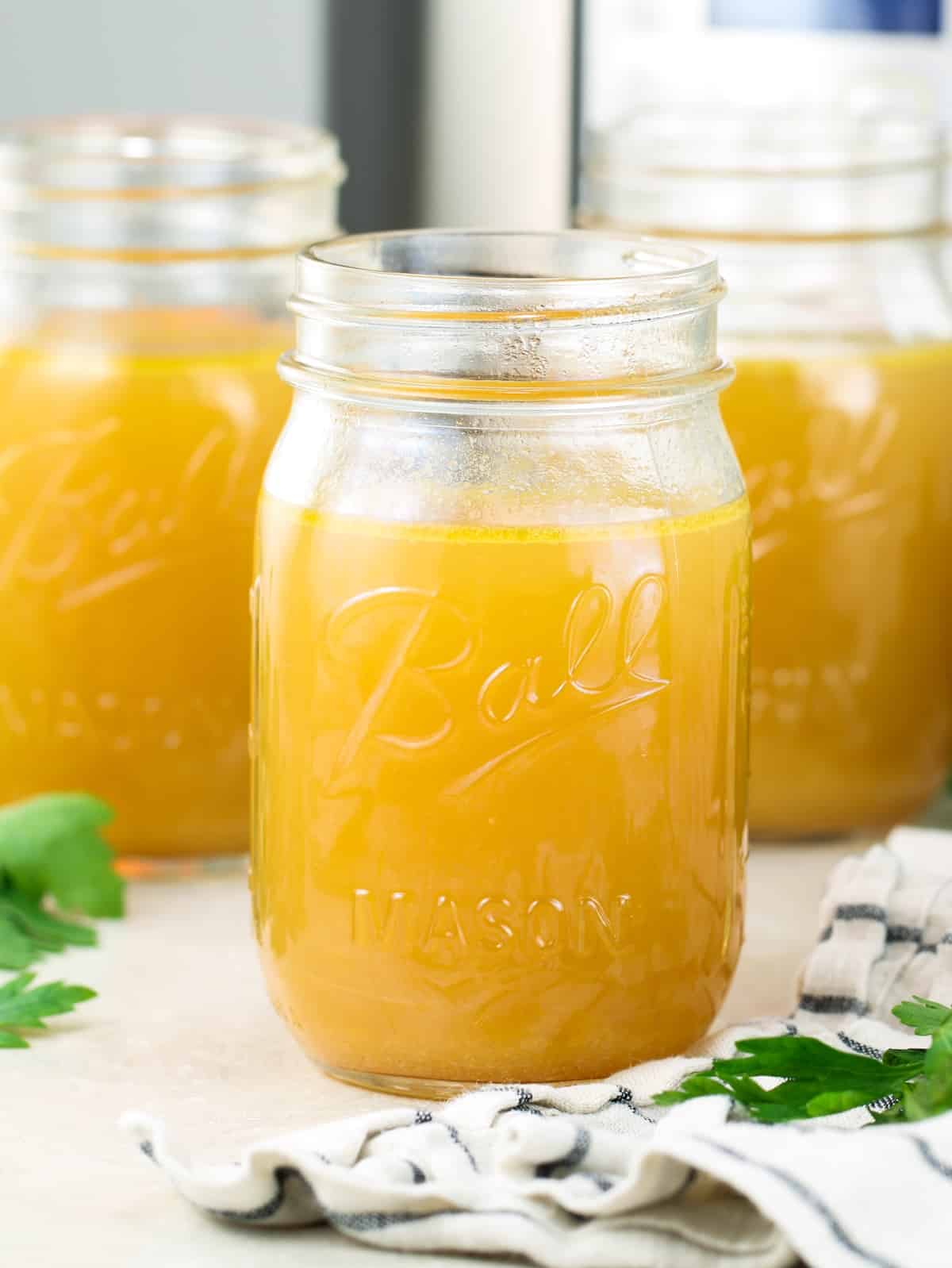 Instant Pot bone broth recipe — rich golden chicken bone broth in a glass jar.