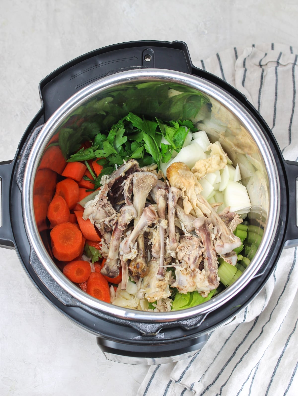 Vegetables, herbs, spices, and bones in the pressure cooker for the Instant Pot bone broth recipe.