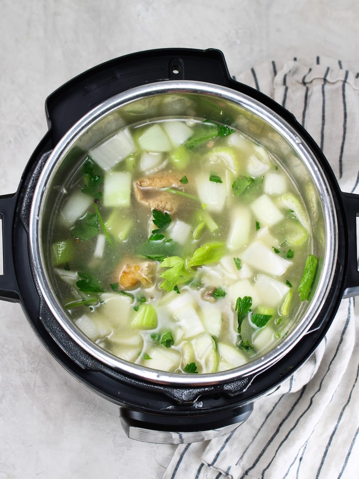 Adding the filtered water and apple cider vinegar to the vegetables and bones.