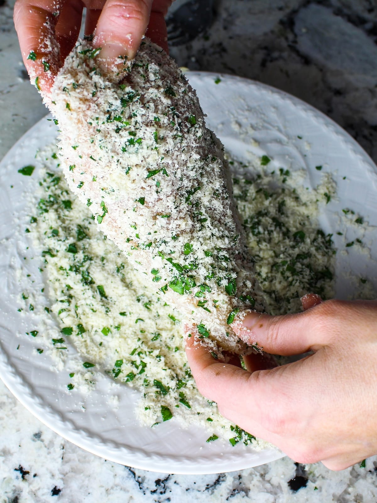 Parmesan crusted chicken breast fully coated in panko and Parmesan, ready to be placed in the baking dish.