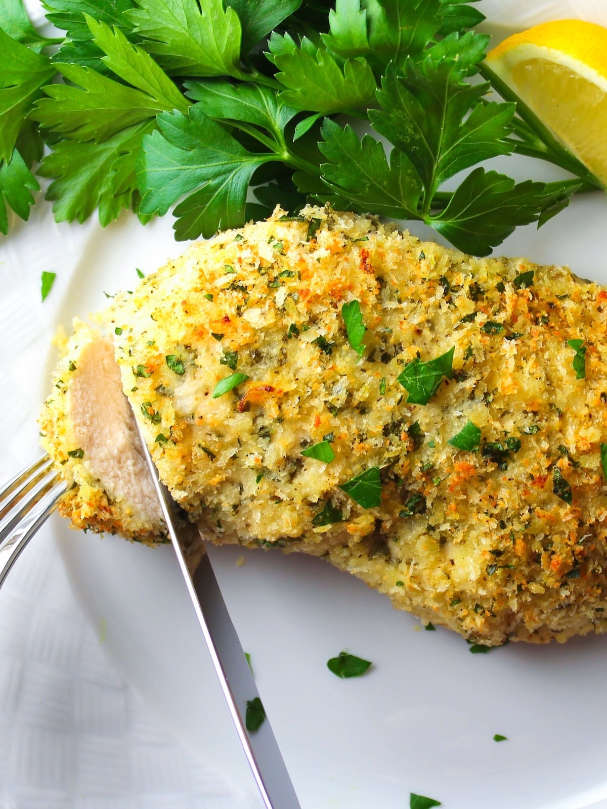 Sliced cheesy Parmesan crusted chicken on a plate showing juicy interior and golden Parmesan coating.
