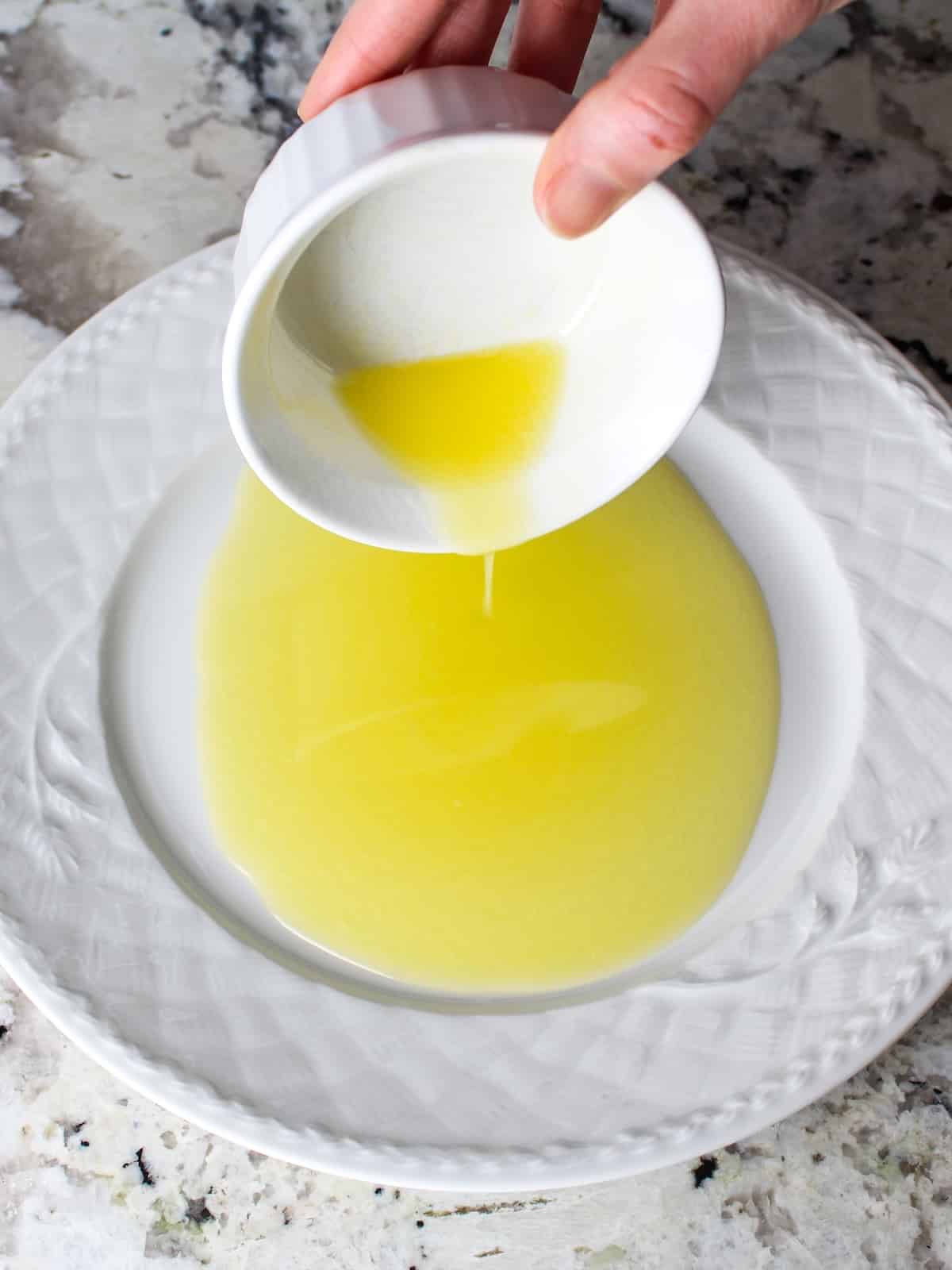 Melted salted butter poured into a shallow dish for the garlic-lemon dredge.