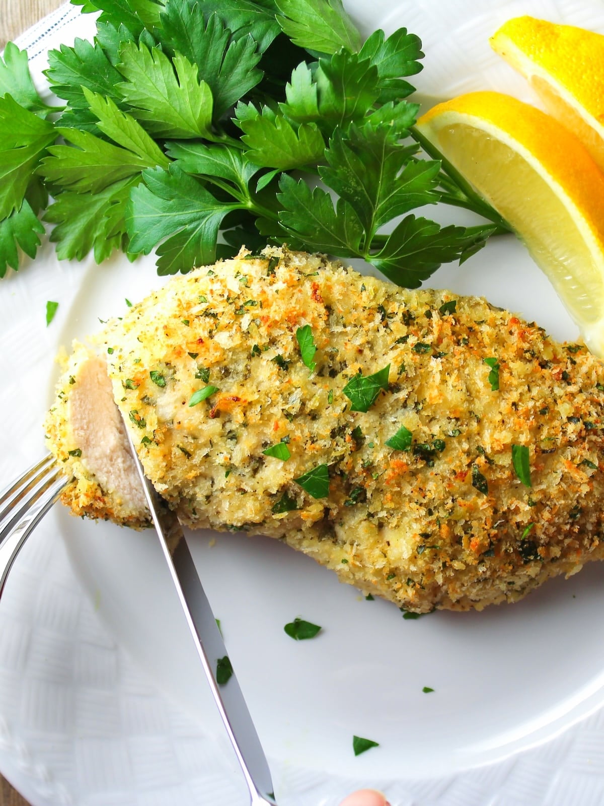 Sliced easy Parmesan crusted chicken recipe on a plate showing juicy interior and golden Parmesan coating.