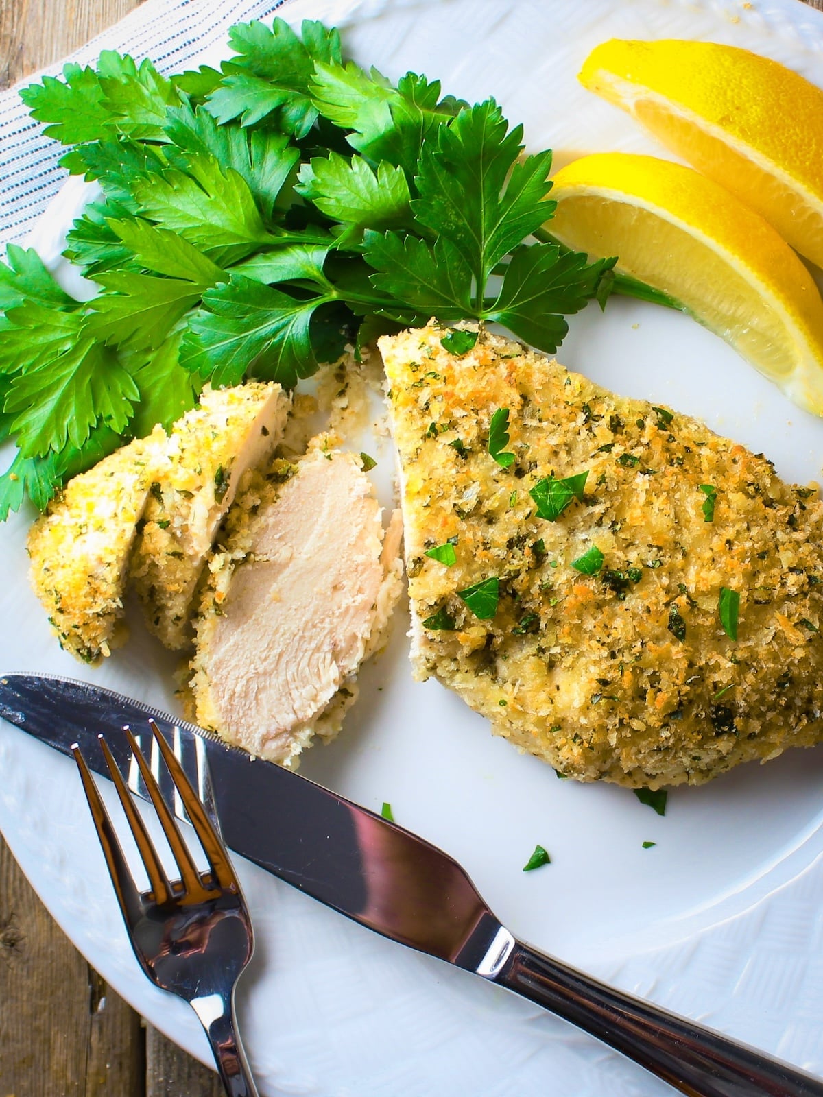Sliced easy Parmesan crusted chicken on a plate showing juicy interior and golden Parmesan coating.