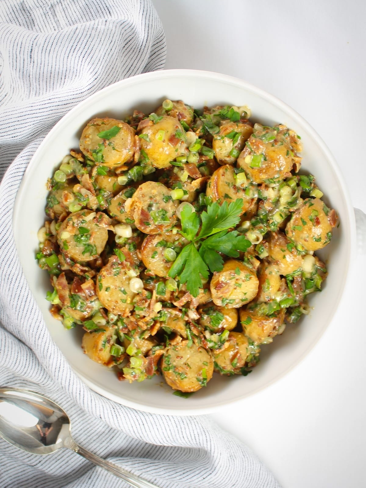 Bacon potato salad tossed in a tangy vinegar dressing with fresh herbs and green onions